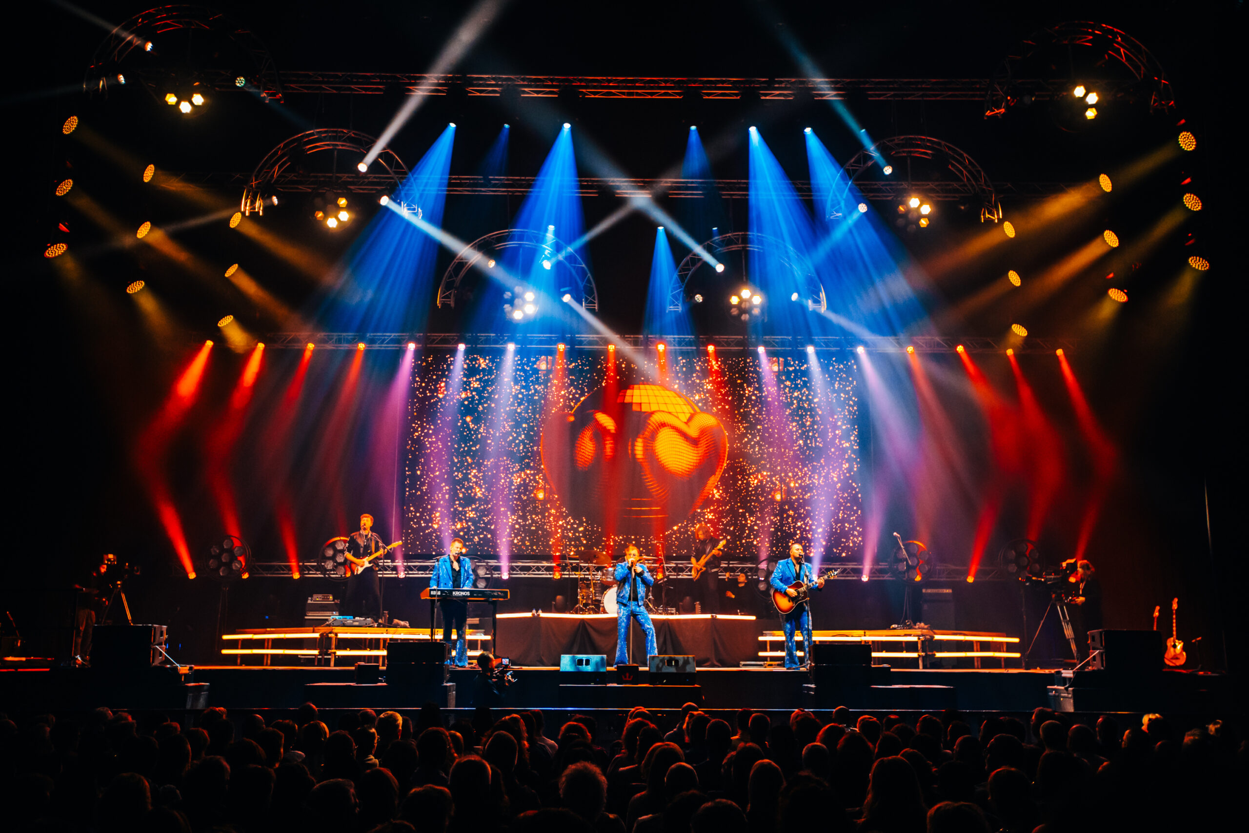 Bunte Scheinwerfer erleuchten eine Bühne während eines Konzerts.