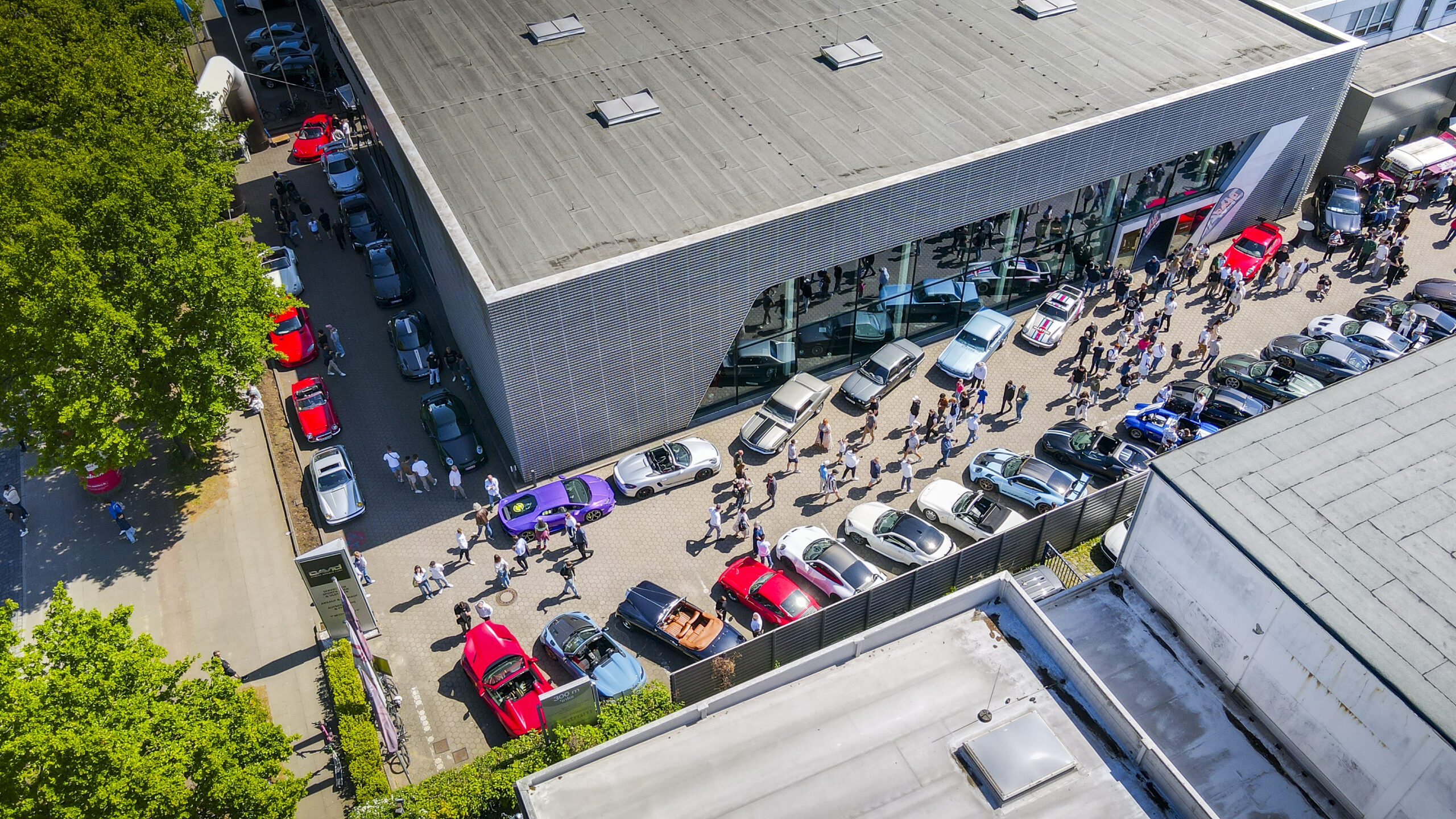e eines großen Autotreffens in Hamburg mit vielen Sportwagen, Oldtimern und Besuchern vor einem Autohaus.