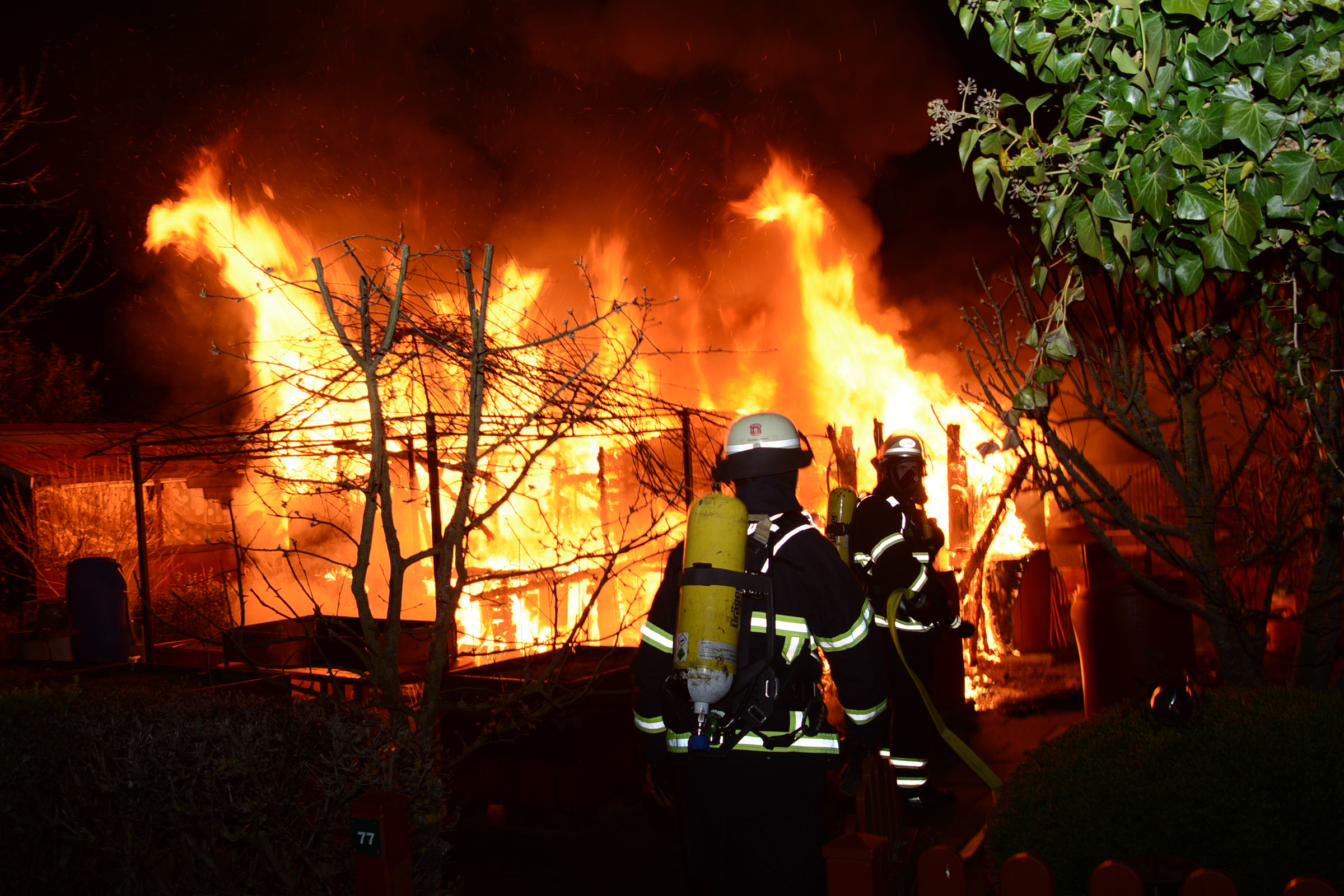 Feuerwehrkräfte vor der brennenden Laube.