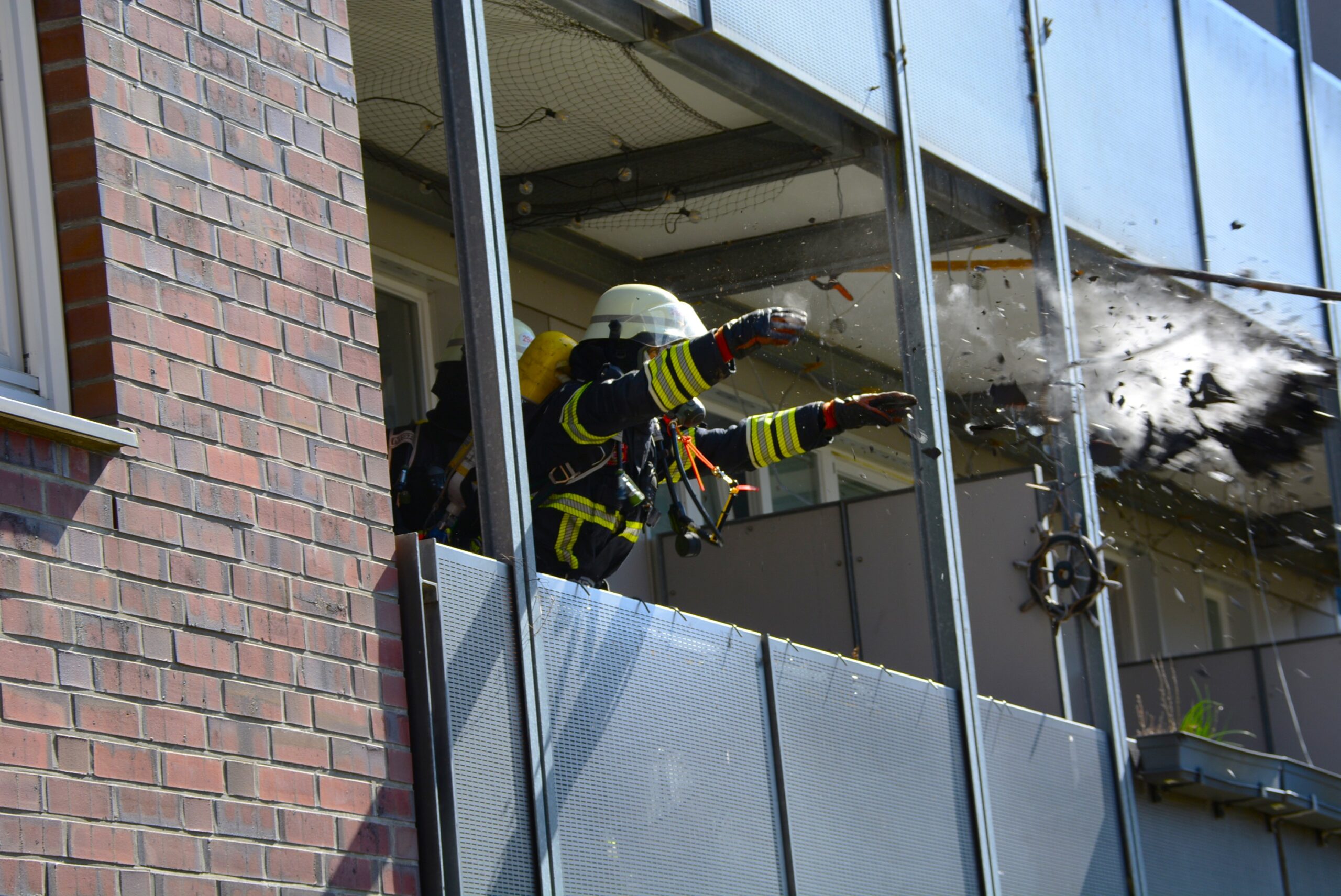 Ein Feuerwehrmann wirft Brandschutz aus dem Fenster der Wohnung in Neuallermöhe.