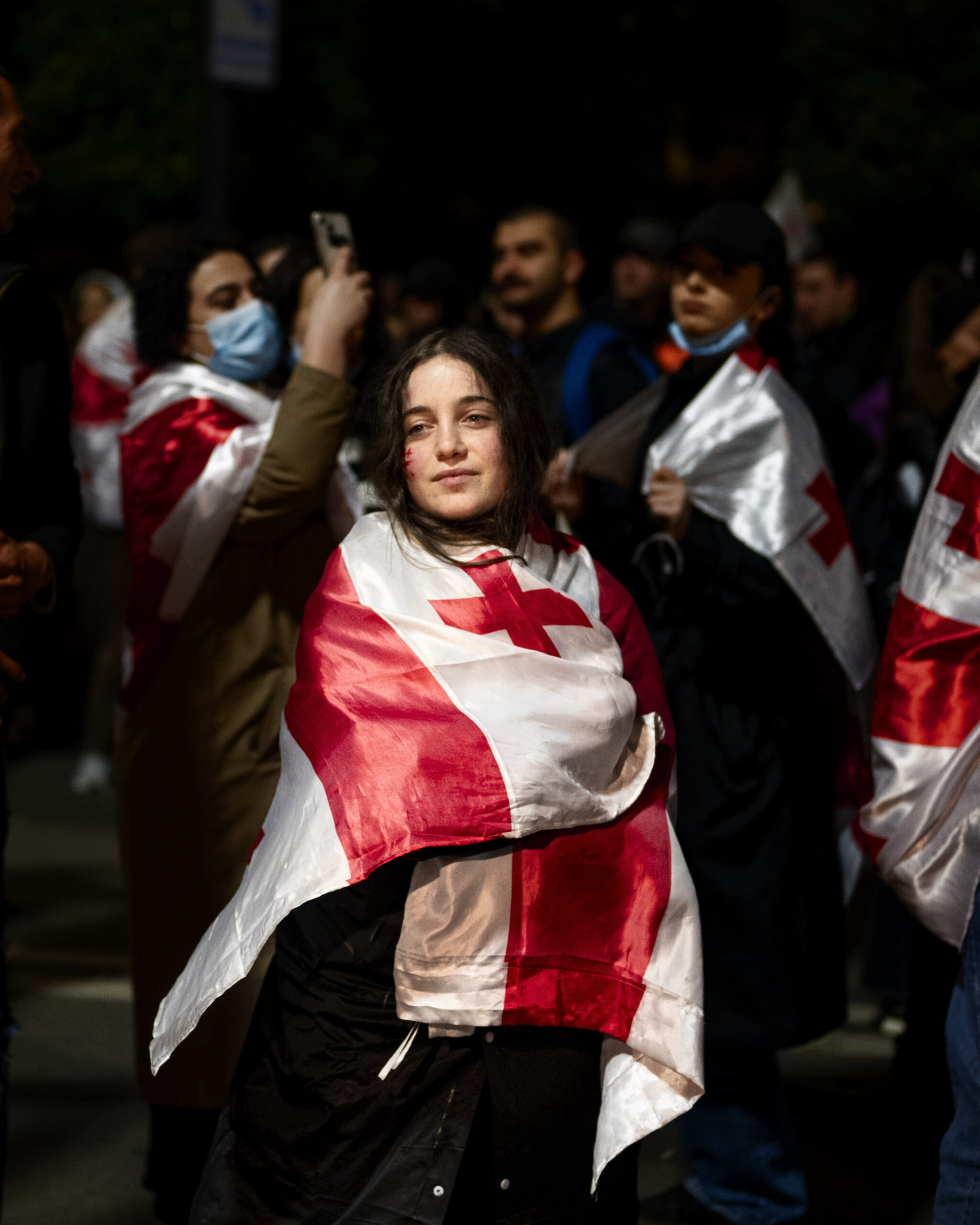Die georgische Flagge liegt auf den Schultern einer jungen Frau.