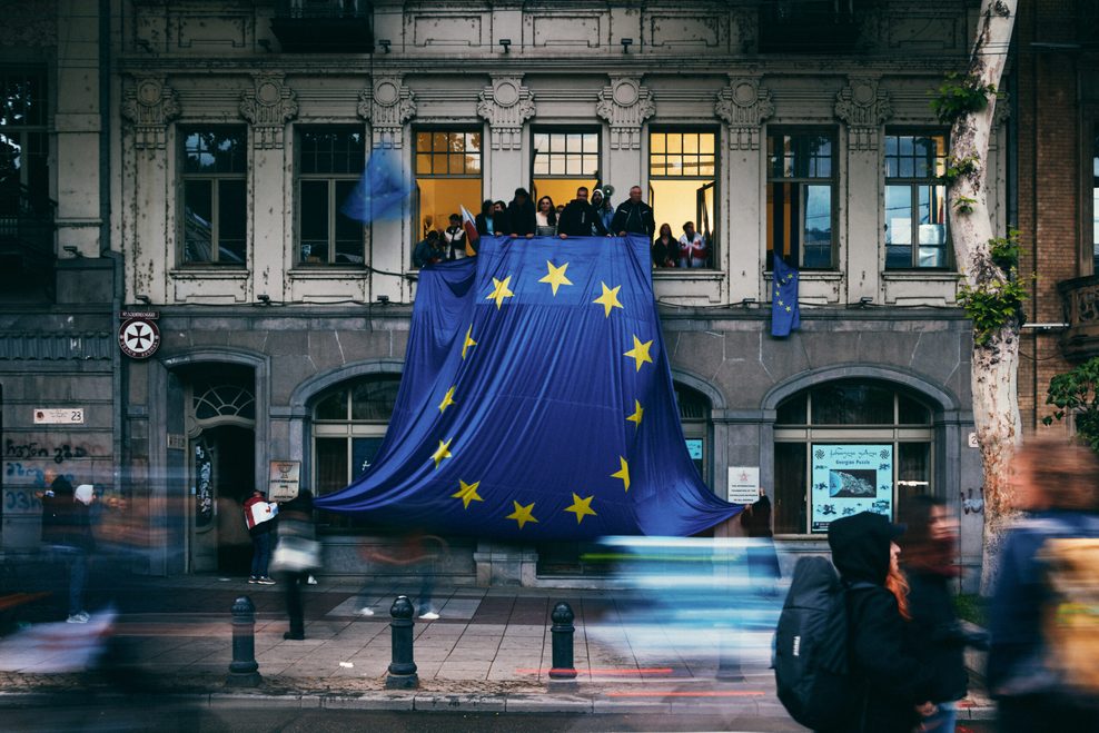 Eine große EU-Flagge hängt an einem Balkon eines Gebäudes.