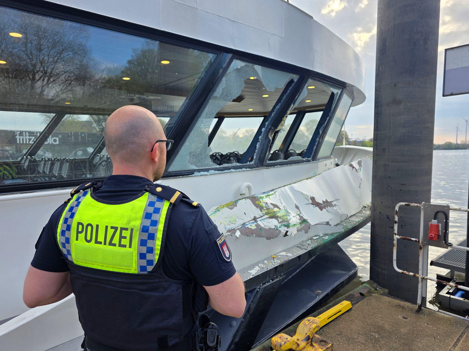 Geborstene Fensterscheiben, verbeulte Bordwand: Ein Polizist untersucht die Schäden an einer der beiden Fähren.