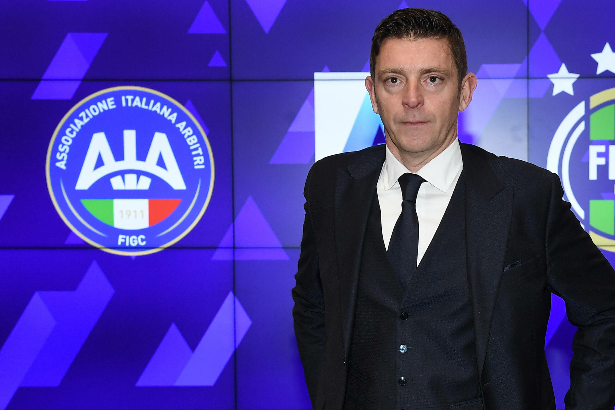 Gianluca Rocchi vor einer blauen Wand mit Italien Logo