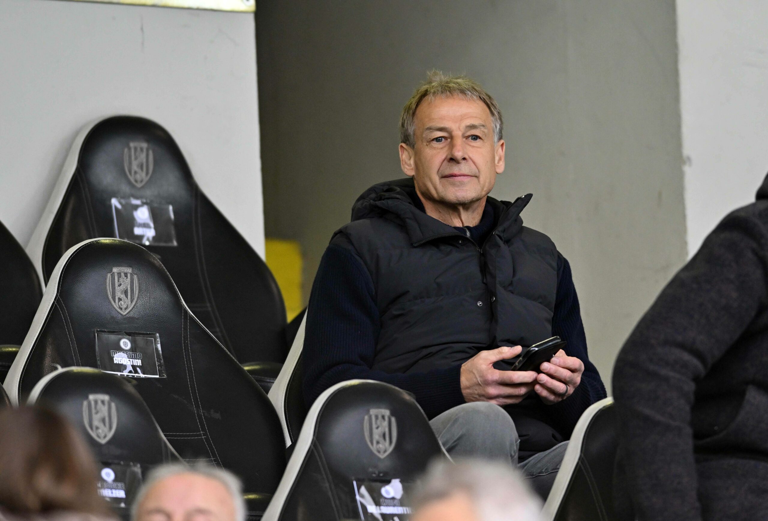 Jürgen Klinsmann sitzt im Stadion auf der Tribüne