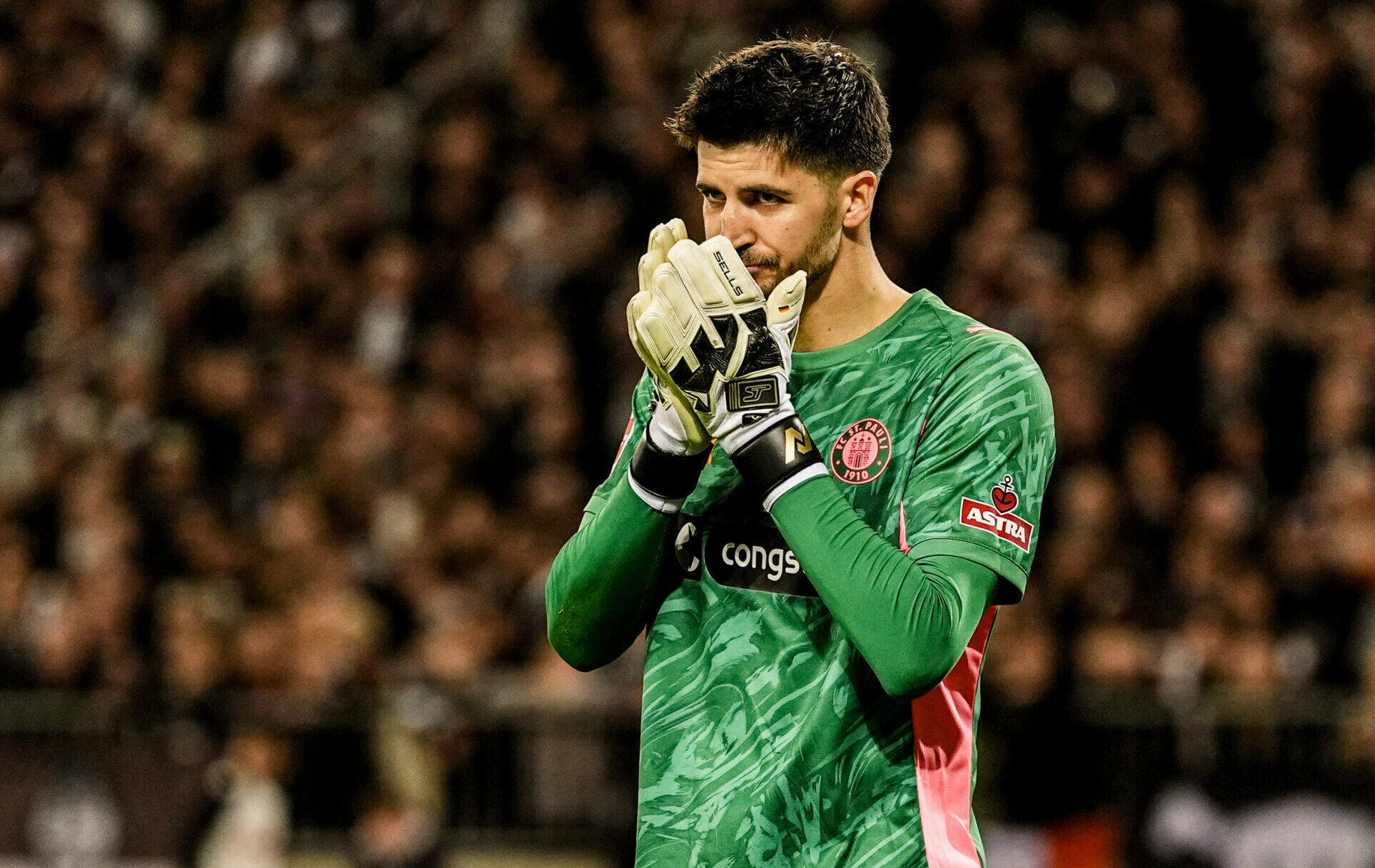St. Pauli-Torwart Nikola Vasilj hält die Handschuhe vor sein Gesicht