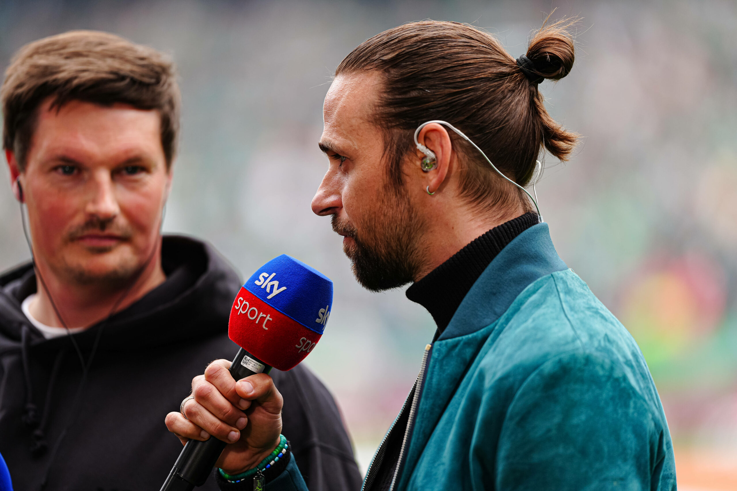 Martin Harnik mit Sky-Mikrofon vor dem Nordderby. Neben ihm steht Merlin Polzin und guckt auf Harnik.