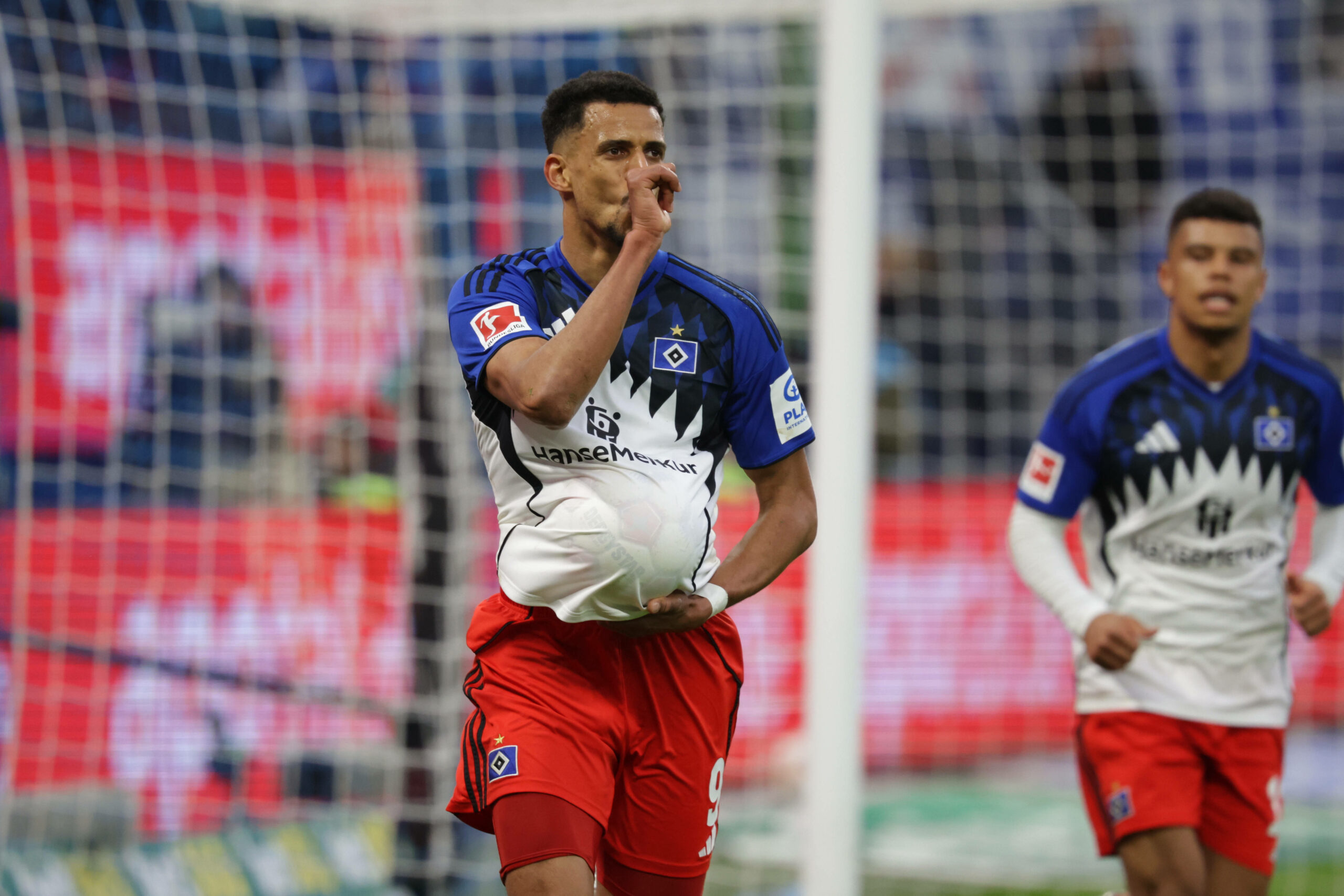 Robert Glatzel hat zum Jubeln den Ball unter seinem Trikot und steckt den Daumen in den Mund