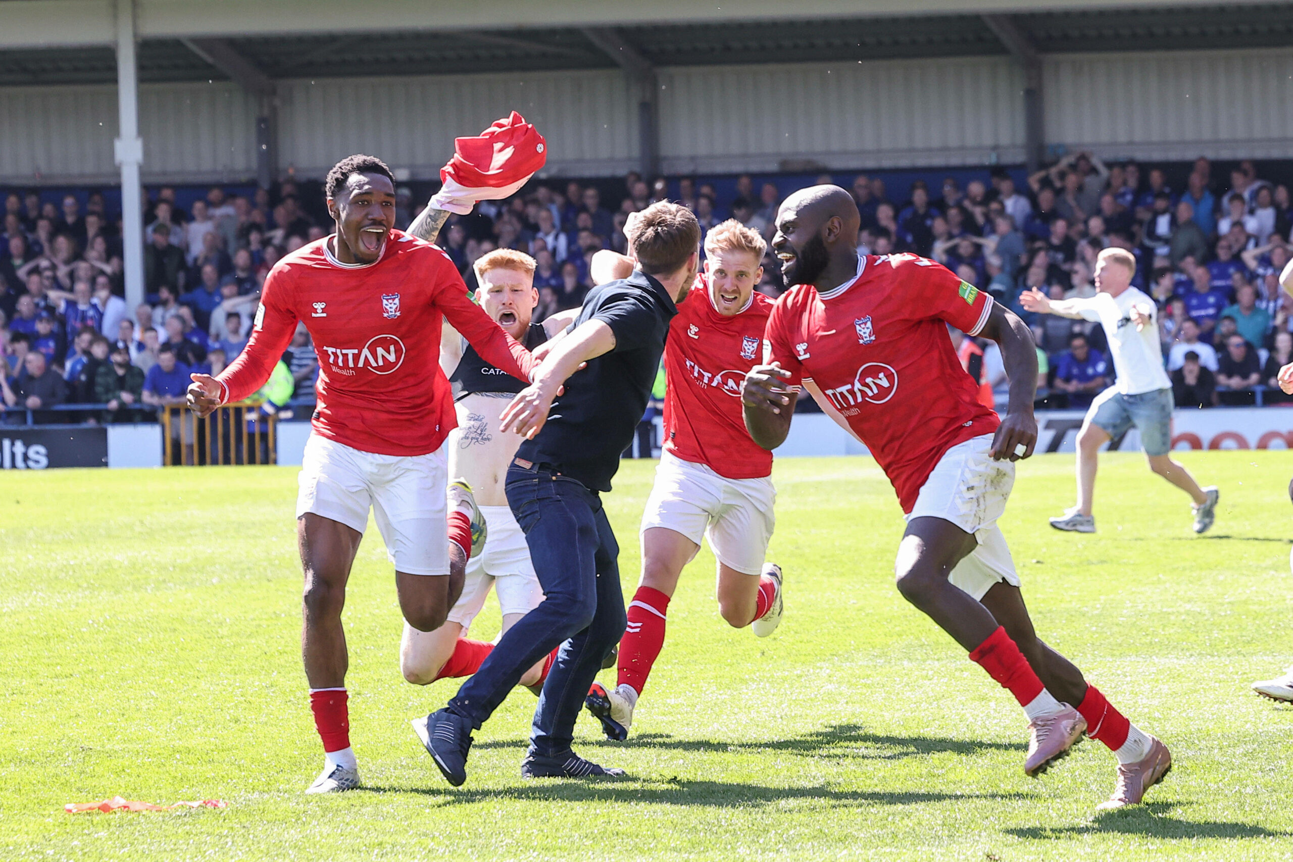 Ein Fan jubelt auf dem Platz mit den Spielern von York City