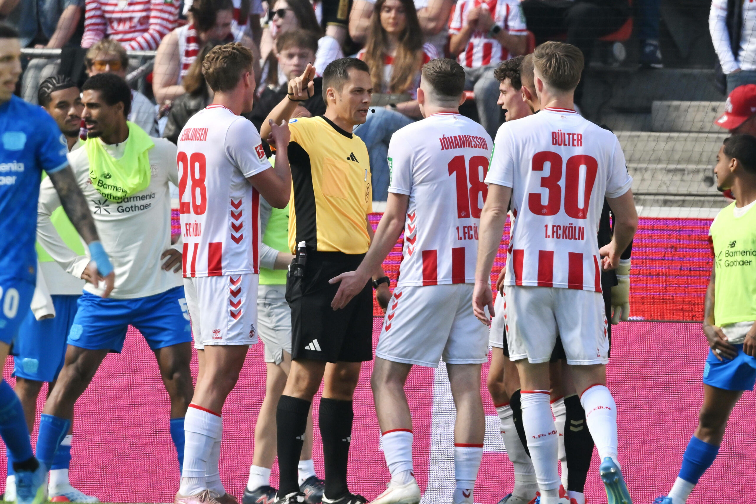 Schiedsrichter Robert Hartmann von Kölner Spielern umkreist.