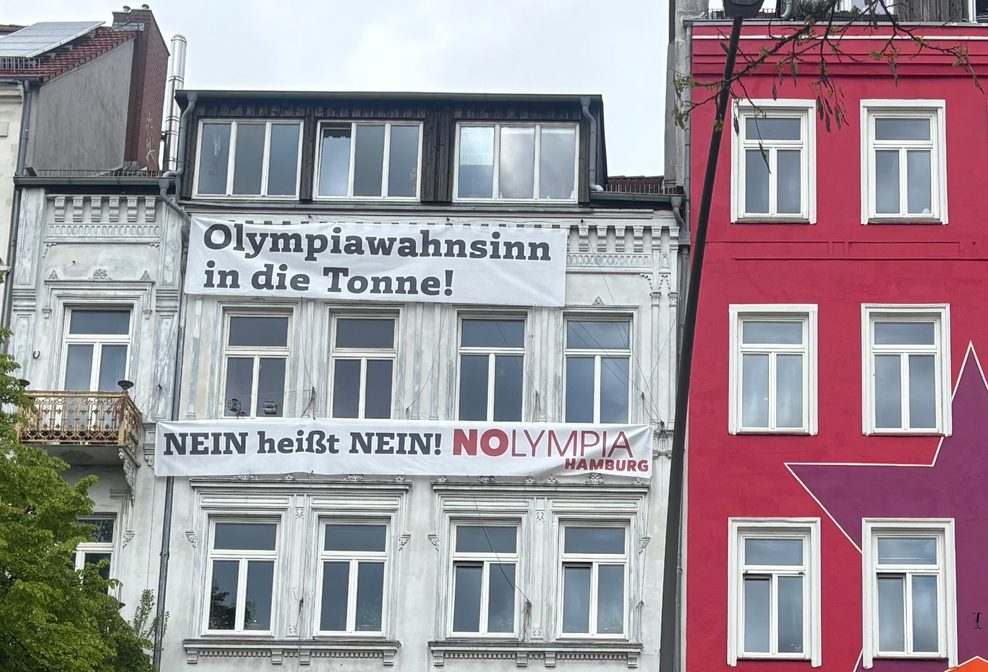 Banner an der Hamburger Hafenstraße mit der Aufschrift „Olympiawahnsinn in die Tonne“ an einem Wohnhaus.