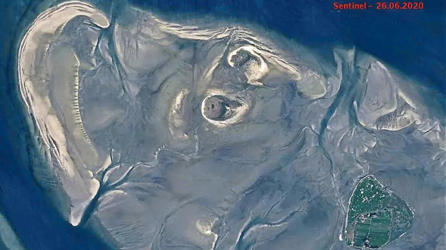 Blick aus dem Weltall auf das Hamburgische Wattenmeer in der Außenelbe. Links oben erkennbar ist die bananenförmige Sandbank, die einmal eine Insel werden könnte. Im Zentrum (kreisförmig) Scharhörn und Nigehörn, rechts unten (grün) das bewohnte Neuwerk.