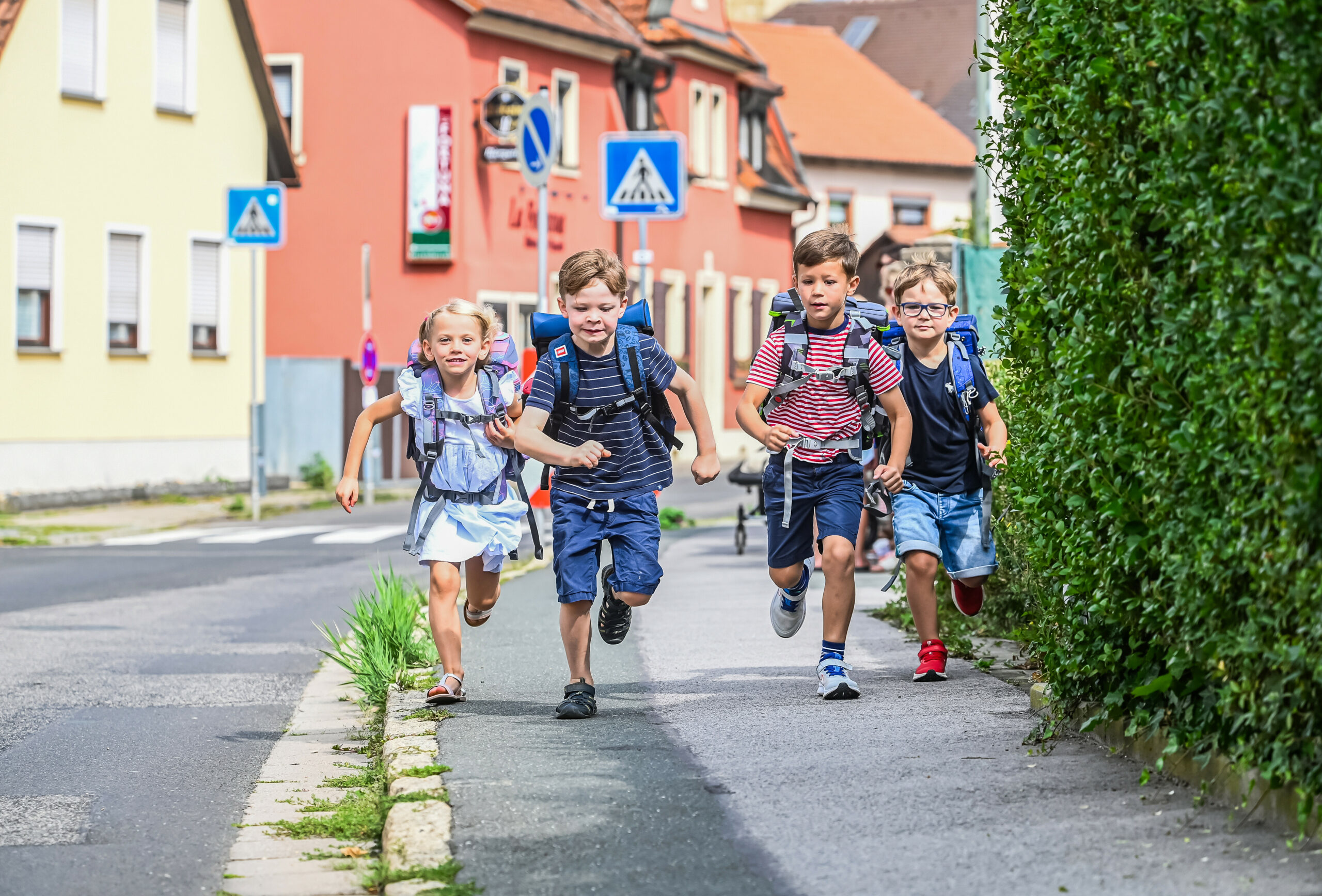 Kinder rennen an einer Straße entlang.