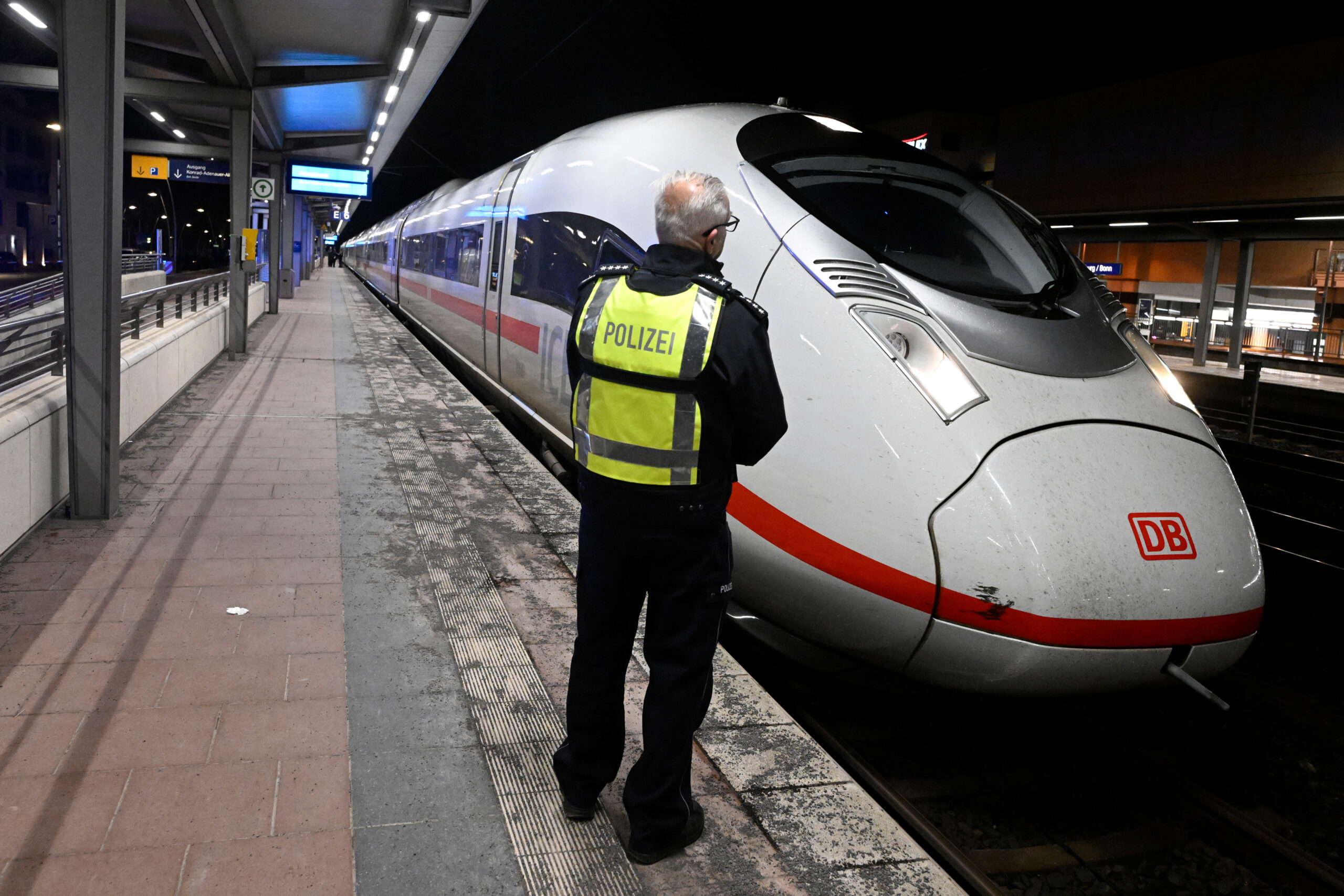 Ein Polizist steht auf einem Bahnsteig im Bahnhof Siegburg, auf dem ein ICE der Deutschen Bahn steht.