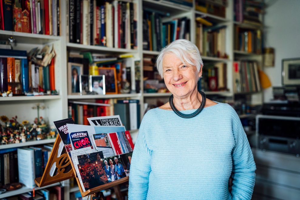 Ältere Dame in blauem Pulli vor Bücherwand