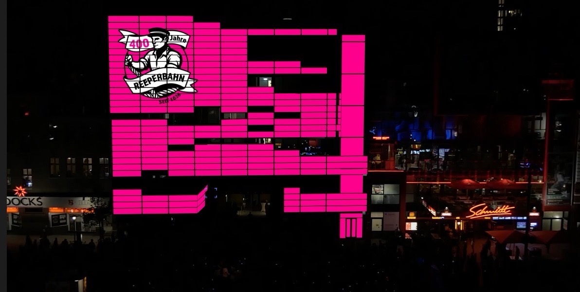 Ein pink beleuchtetes Gebäude mit der Aufschrift „400 Jahre Reeperbahn“