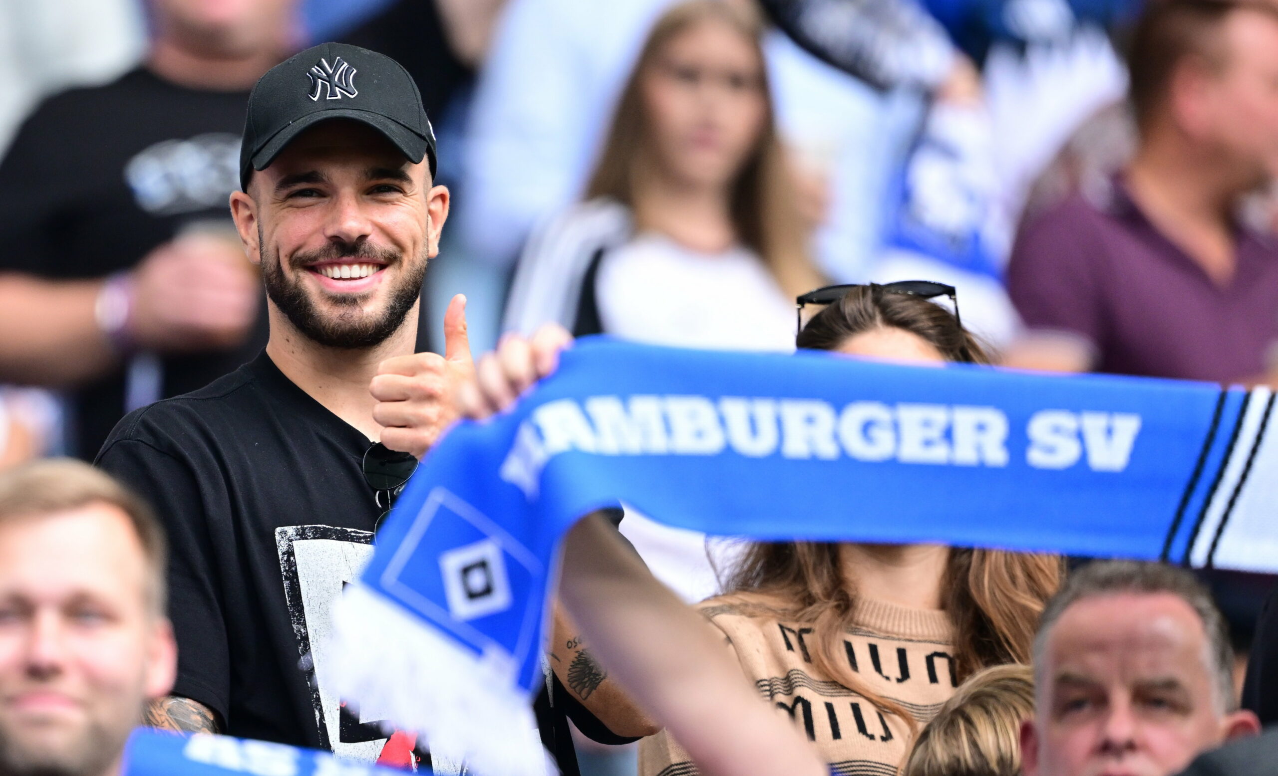 Mario Vuskovic lächelt auf der Tribüne beim Besuch eines HSV-Heimspiels