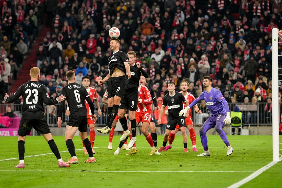 Karol Mets und Eric Smith von St. Pauli köpfen vergeblich gegen Luis Diaz von Bayern München