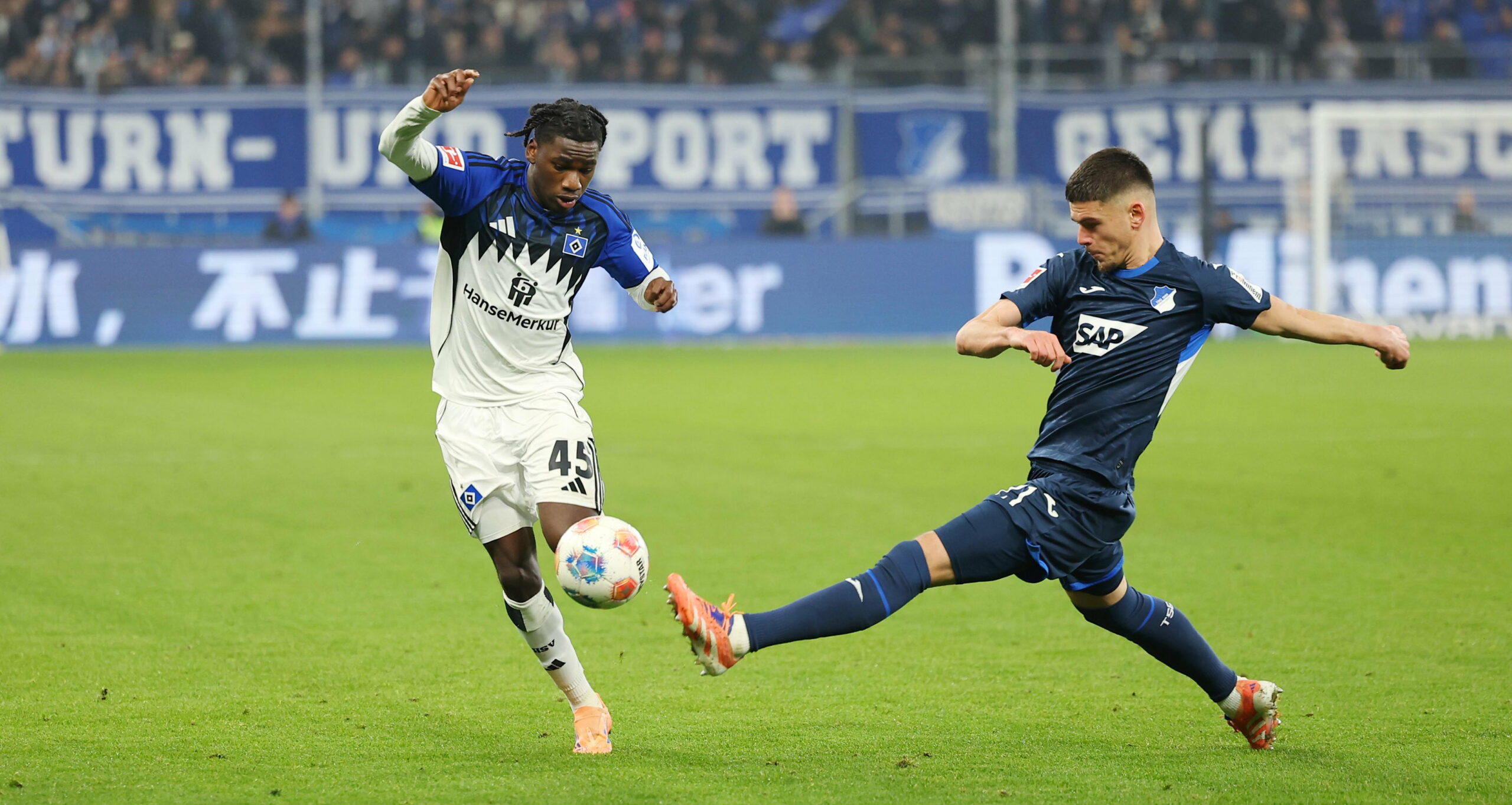 Fabio Baldé vom HSV im Zweikampf mit Albian Hajdari von Hoffenheim vor einer TV-Kamera von Sky
