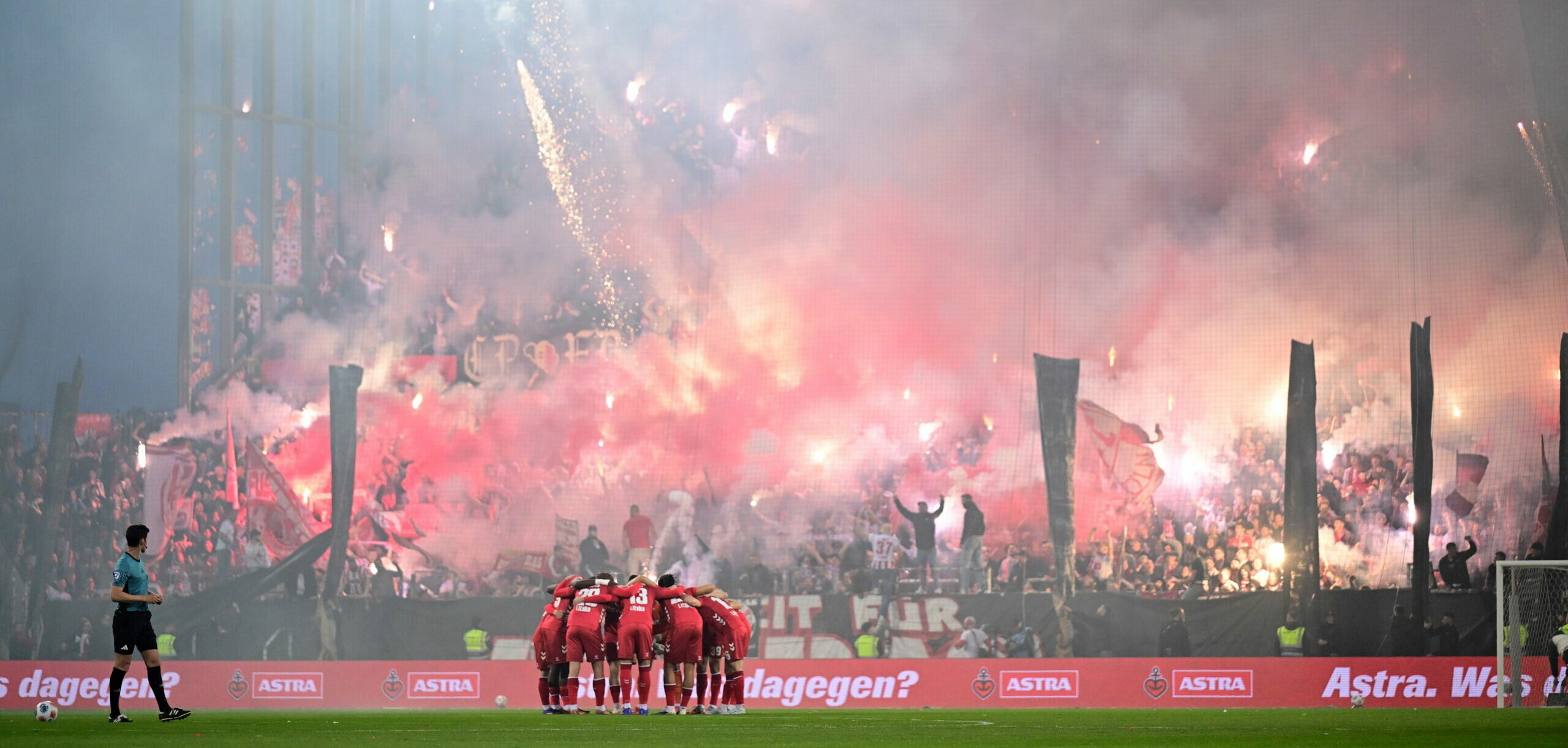 Die Kurve mit den Kölner Fans im Millerntorstadion ist von Pyrotechnik hell erleuchtet