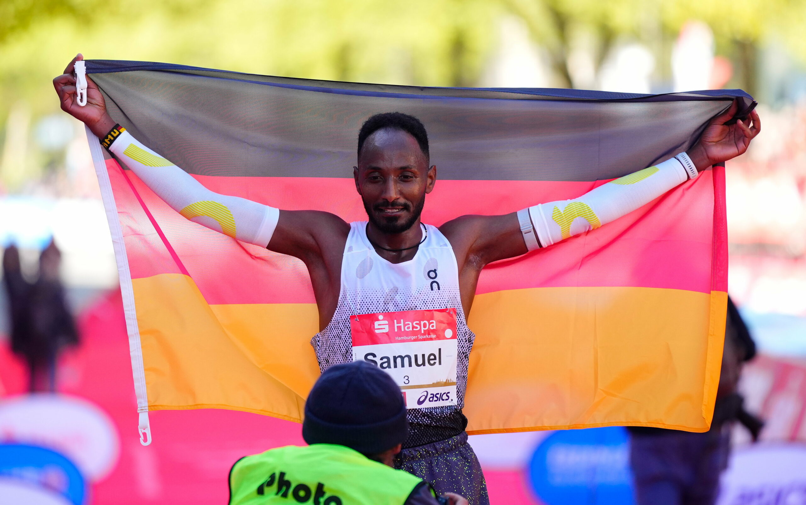 Samuel Fitwi mit einer Deutschland Flagge nach seinem Zieleinlauf