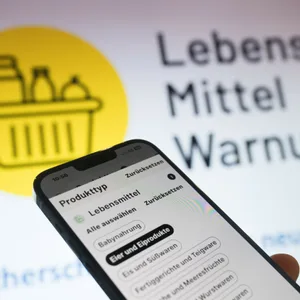 Handy vor Bildschirm „Lebensmittelwarnung“