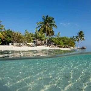 Eine Insel der Malediven vor blauem Himmel.