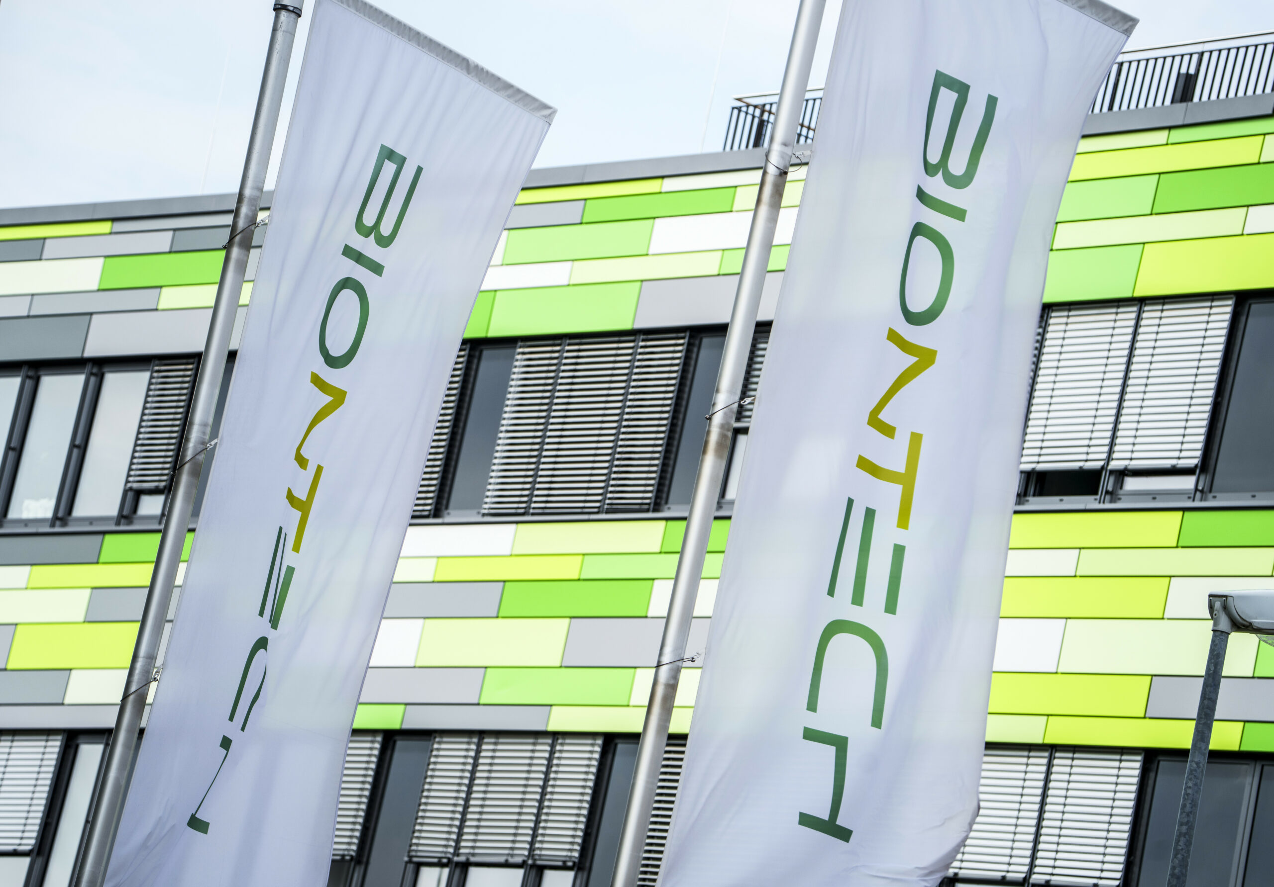 Die Flaggen des Pharma-Unternehmens Biontech flattern vor der Firmenzentrale im Wind.