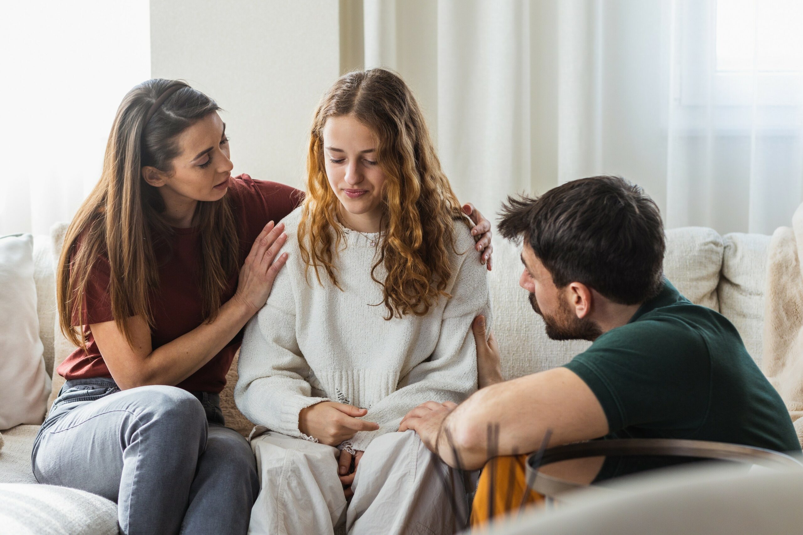 Zwei Personen trösten einen Teenager.