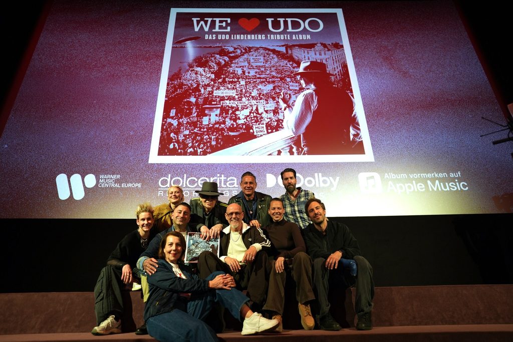 Udo Lindenberg präsentiert sich mit anderen Künstlern auf einer Bühne unter dem neuen Albumcover