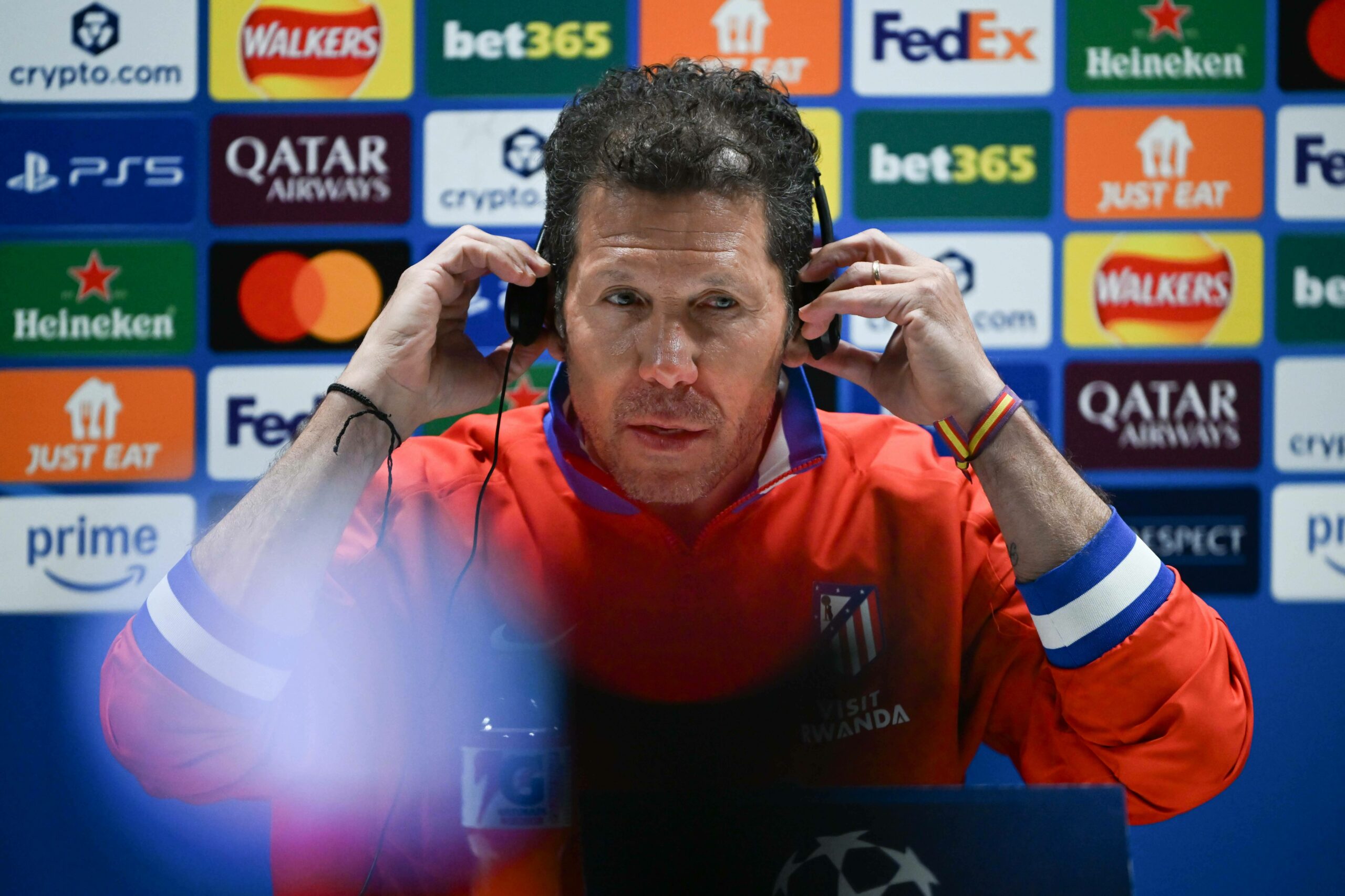 Atlético-Trainer Diego Simeone nimmt sich Übersetzungskopfhörer vom Ohr bei der Pressekonferenz vor dem Spiel beim FC Arsenal.