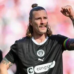St. Pauli-Kapitän Jackson Irvine mit kämpferisch erhobener Faust vor der Fankurve