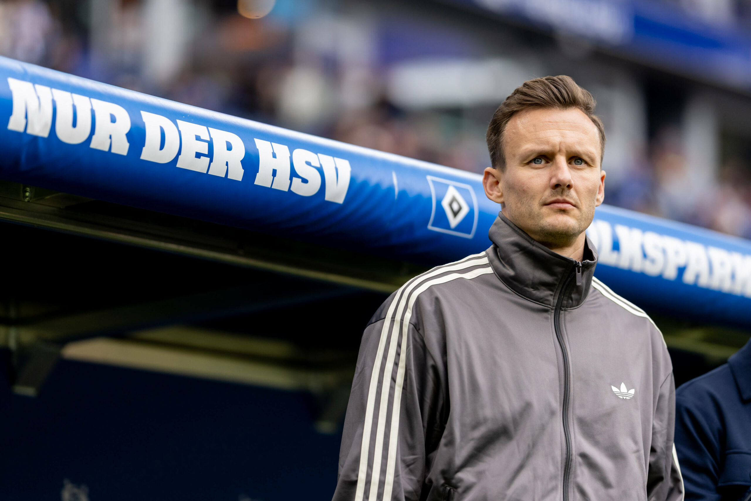 HSV-Sportdirektor Claus Costa steht vor dem Bundesligaspiel gegen Freiburg vor der HSV-Ersatzbank.