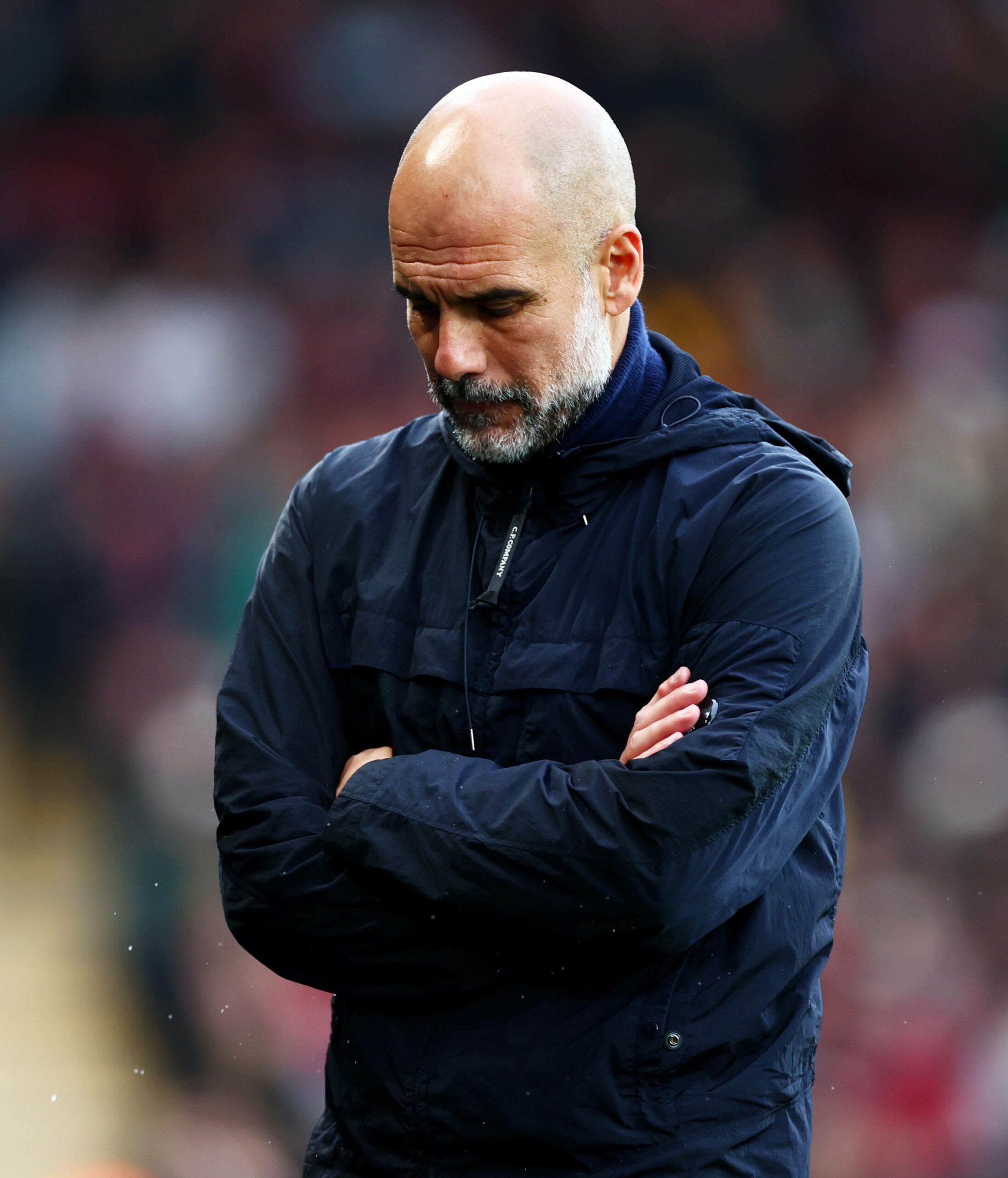 Pep Guardiola mit verschränkten Armen und Blick nach unten