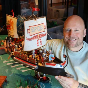 Ein Mann hält ein Playmobil-Schiff in den Händen.