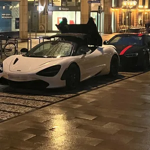 Weißer McLaren 720S Spider steht nachts bei Regen in der Hamburger Rathausstraße mit teilweise geöffnetem Verdeck am Straßenrand. Hinter dem Sportwagen parkt ein schwarzer Audi R8.