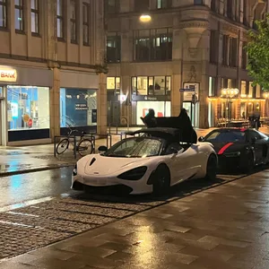 Weißer McLaren 720S Spider steht nachts bei Regen in der Hamburger Rathausstraße mit teilweise geöffnetem Verdeck am Straßenrand. Hinter dem Sportwagen parkt ein schwarzer Audi R8.
