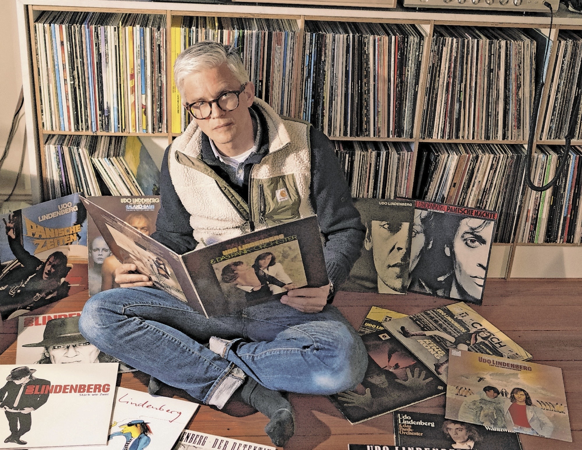 MOPO-Verleger Arist von Harpe sitzt zwischen vielen Schallplatten von Udo Lindenberg.