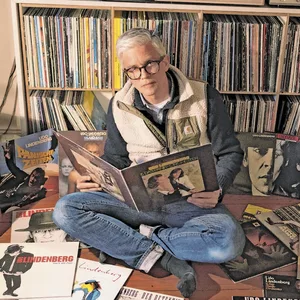MOPO-Verleger Arist von Harpe sitzt zwischen vielen Schallplatten von Udo Lindenberg.