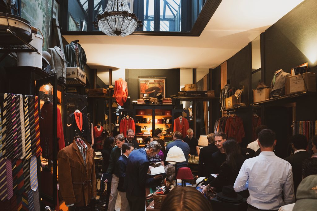 Zahlreiche Gäste füllen einen Laden für klassische Herrenmode und Vintage-Kleidung.